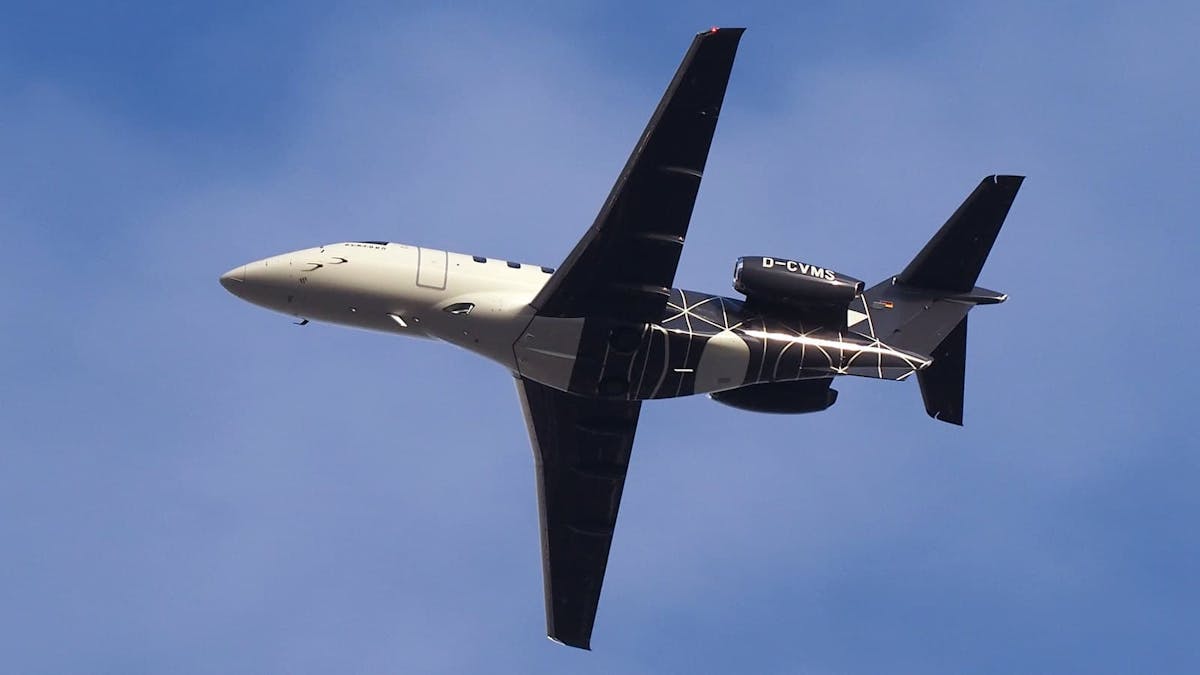 A photo from below of a Pilatus PC-24 with black tron style accents in the rear fuselage.